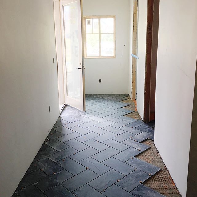 an empty room with tile flooring and door leading to another room in the background