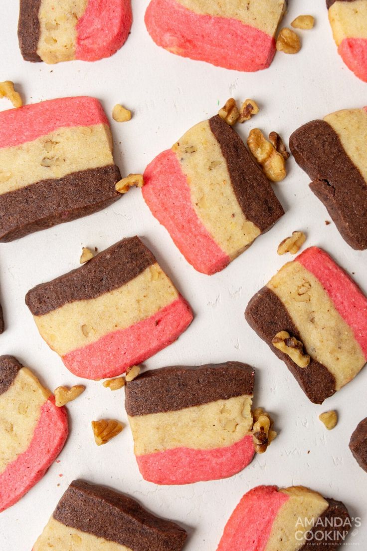 several cookies with different colored frosting and nuts