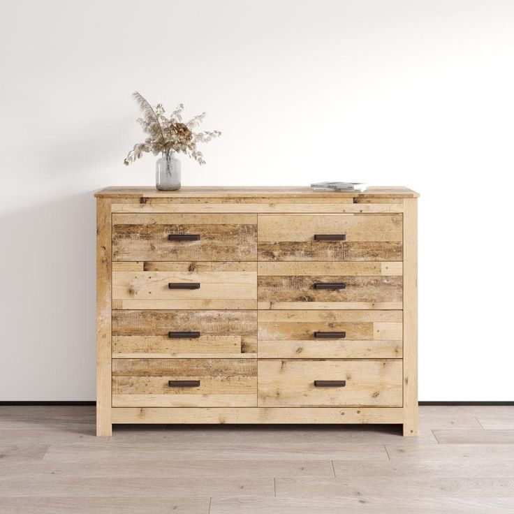 a wooden dresser sitting on top of a hard wood floor next to a white wall