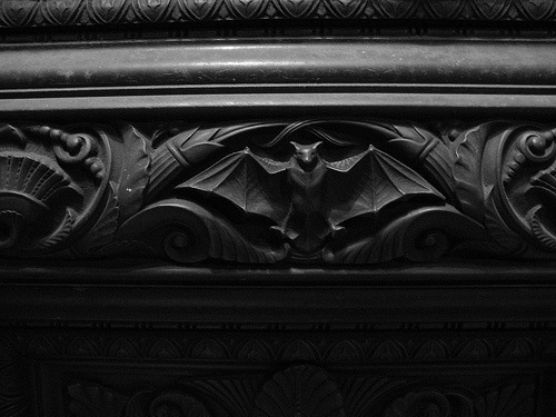 a black and white photo of an intricately carved column with bats on it's sides