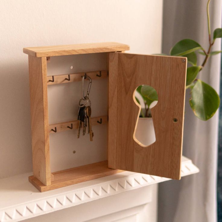 a wooden box with keys in it and a potted plant on the shelf next to it