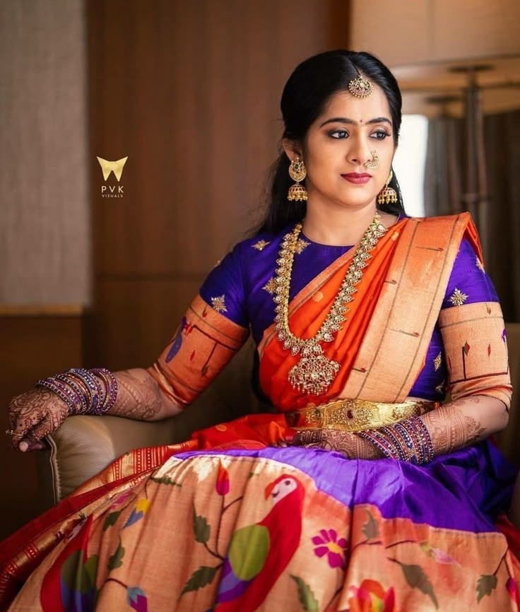 a woman sitting in a chair wearing an orange and purple sari