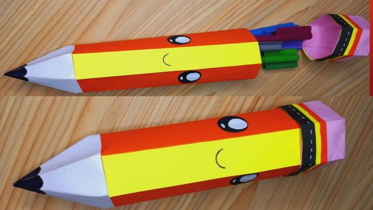 two crayon pencils with faces drawn on them sitting on top of a wooden table