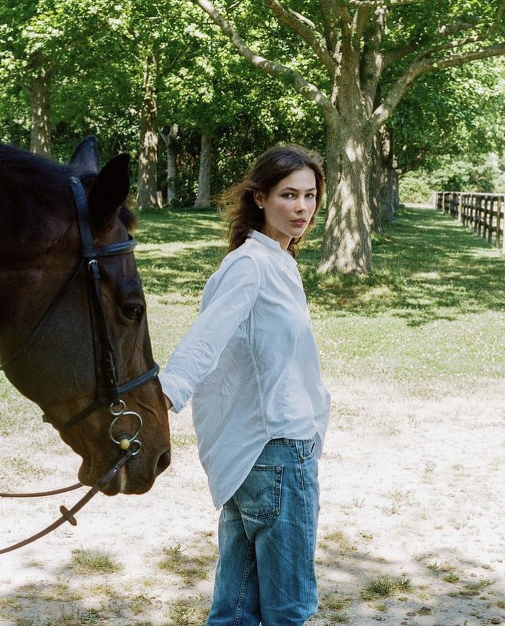 a woman standing next to a brown horse