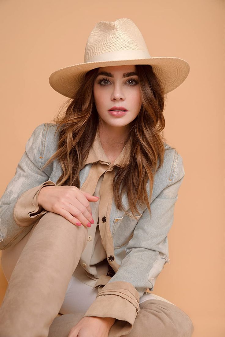 a woman wearing a hat sitting on the ground