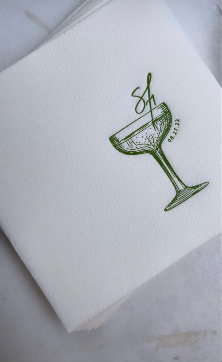 a white napkin with a green design on the side and a wine glass drawn on it