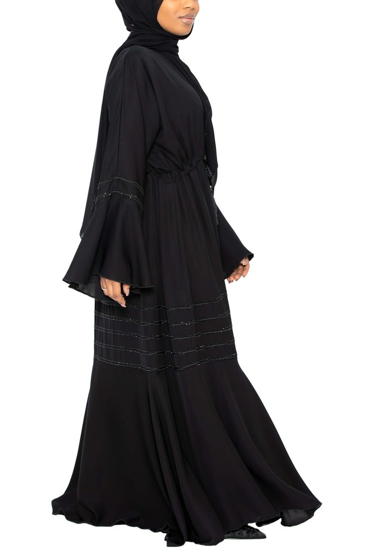 Add a touch of style with our beautiful Suhayla Abaya in Classic Black. This umbrella-cut abaya offers a wide sweep for a graceful, elegant flow. With elegant stonework adorning the sleeves and peplum, this gorgeous piece will have you looking absolutely amazing. Made with silky Nida Open abaya with hidden buttons A-line cut for a modest fit Model is 5'5 and is wearing a size 56 Includes a matching scarf Honey Dip Scarf in Classic Black (shown above) sold separately Made in Dubai Luxury Black Abaya For Spring, Luxury Black Abaya For Party, Luxury Long Black Abaya, Luxury Formal Black Abaya, Luxury Black Spring Abaya, Luxury Fitted Black Abaya, Luxury Black Elegant Niqab, Luxury Black Long Sleeve Abaya, Honey Dip