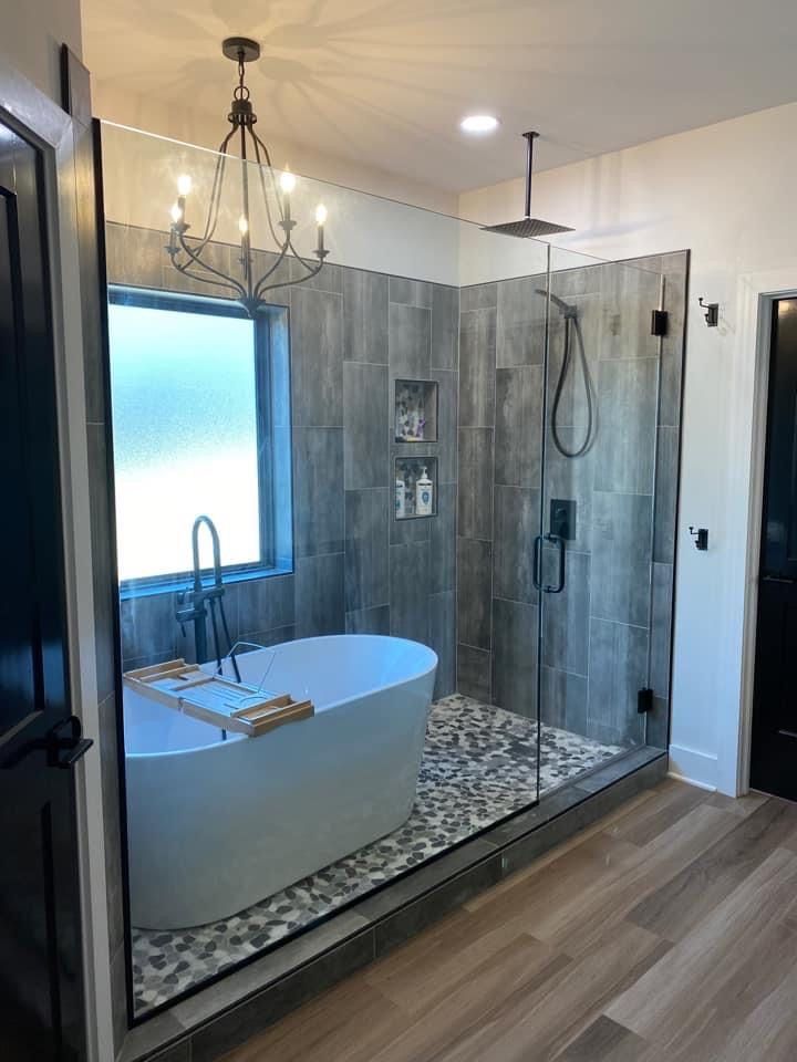 a bathroom with a large bathtub next to a walk in shower and a chandelier