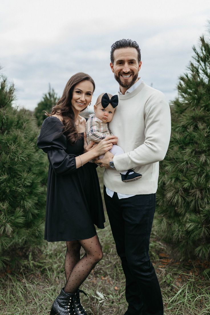 a man and woman holding a baby in their arms while standing next to each other