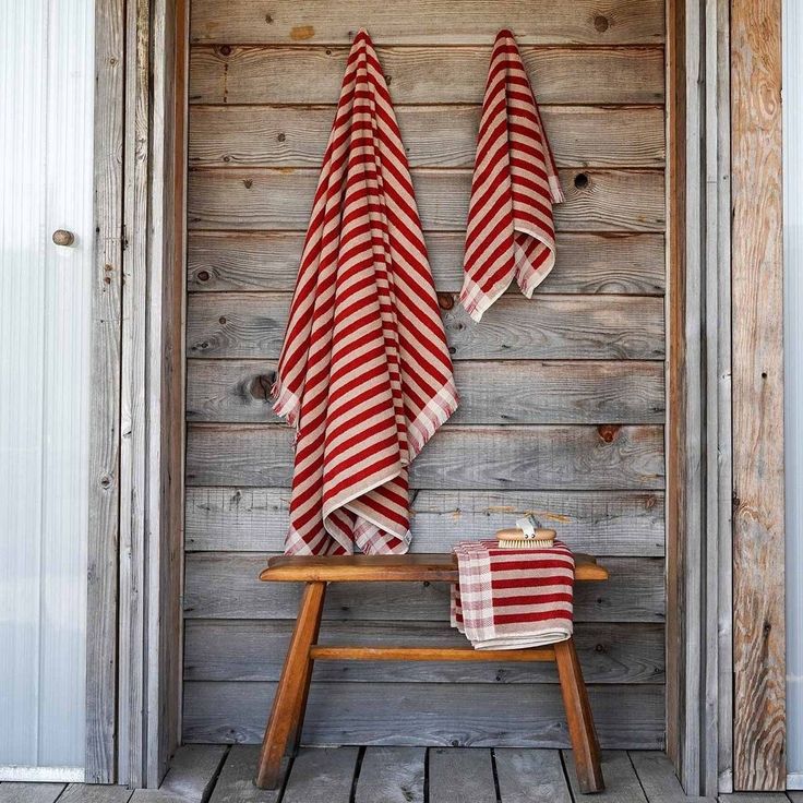 two red and white striped towels hanging on the wall next to a wooden bench with an open door