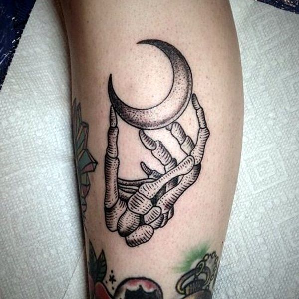 a black and white tattoo on the leg of a person with a moon above it