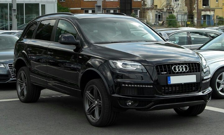 an audi suv is parked in a parking lot next to other cars on the street