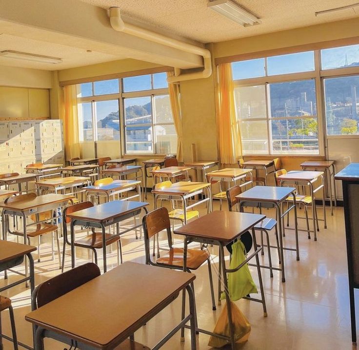 an empty classroom with desks and chairs in front of large windows looking out onto the water