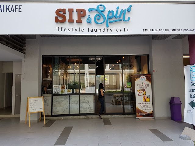 a woman standing in front of a store with an advertisement on the door and sign for sip & spirit