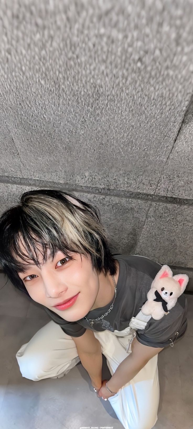 a woman with short black hair sitting on the floor holding a stuffed animal in her hand