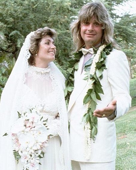 a man and woman dressed in wedding attire standing next to each other on the grass