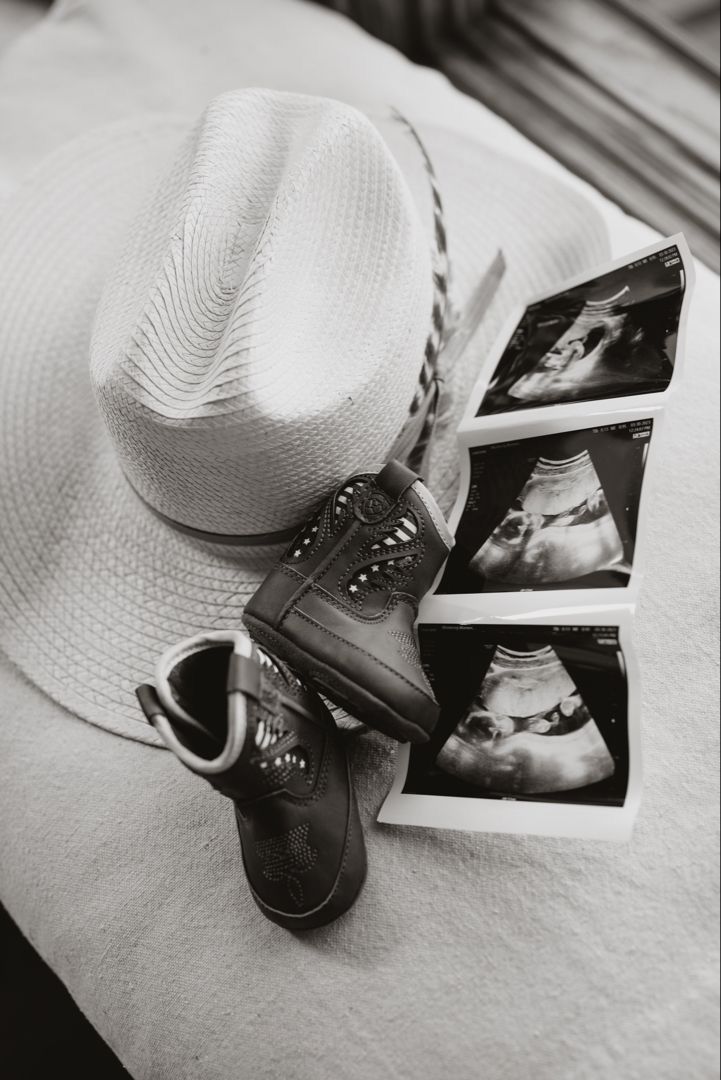 a cowboy hat, booties, and other items are arranged on a bed