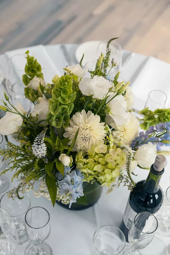 there is a vase with flowers on the table next to wine glasses and an empty bottle