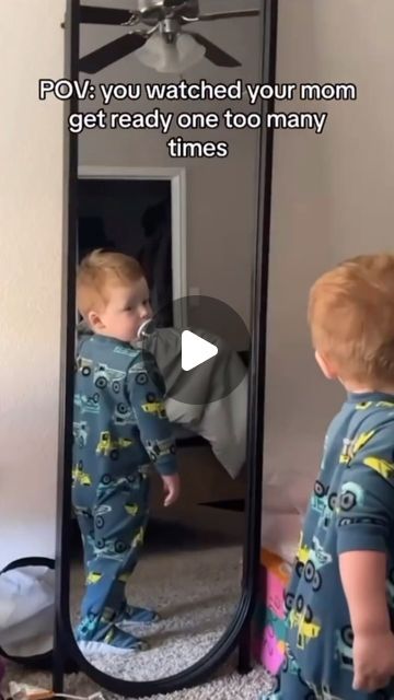 a young boy standing in front of a mirror looking at himself in the mirror,