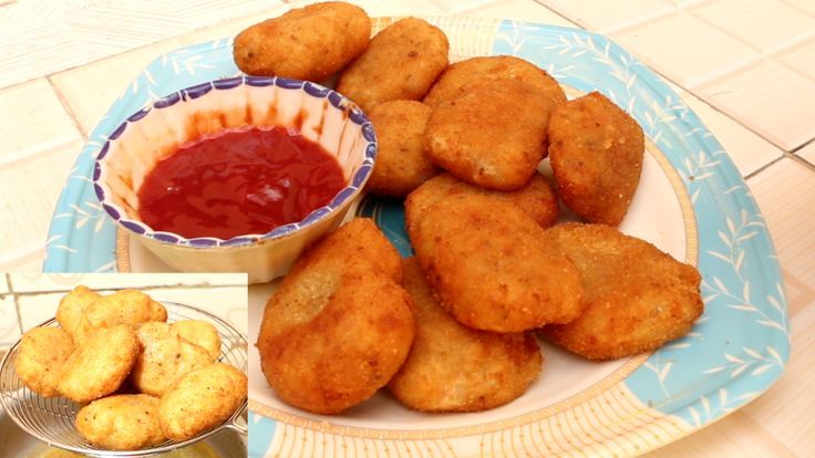 some fried food is sitting on a plate with ketchup and sauce in a bowl