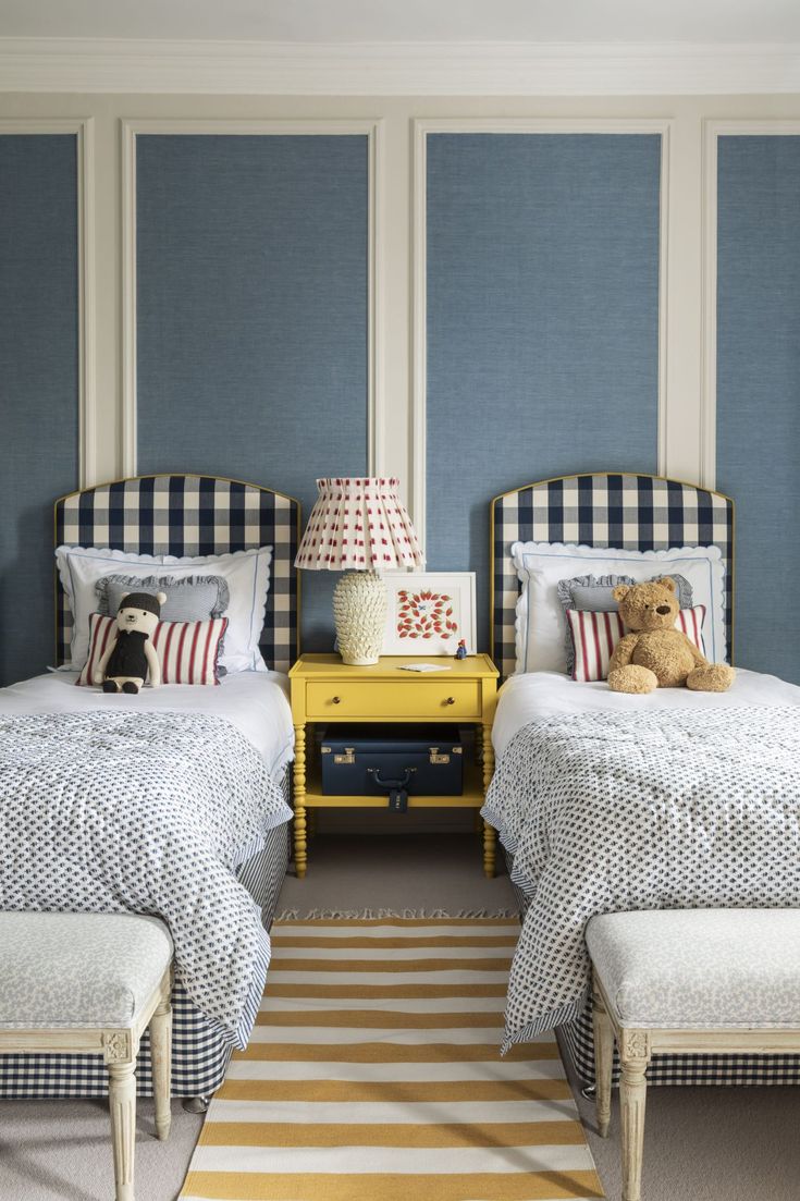 two twin beds in a bedroom with blue and white striped wallpaper on the walls