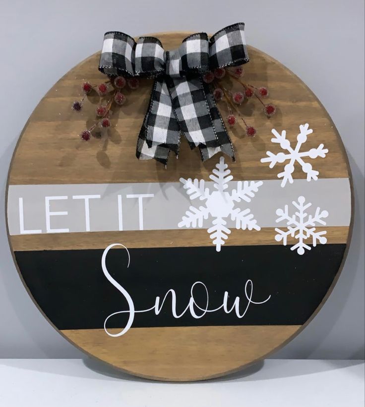 a wooden sign that says let it snow on the front and side of it with a bow