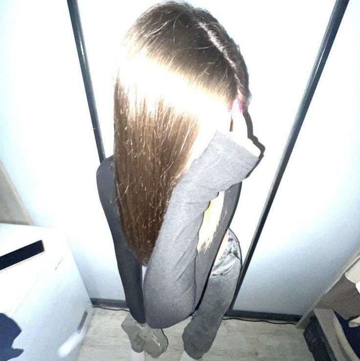 a woman standing in front of a refrigerator with her hair hanging back to the side