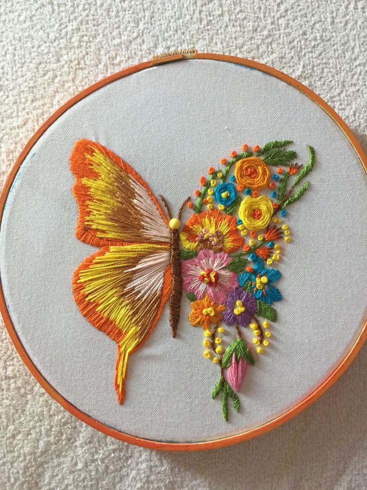 an embroidered butterfly and flowers on a white background