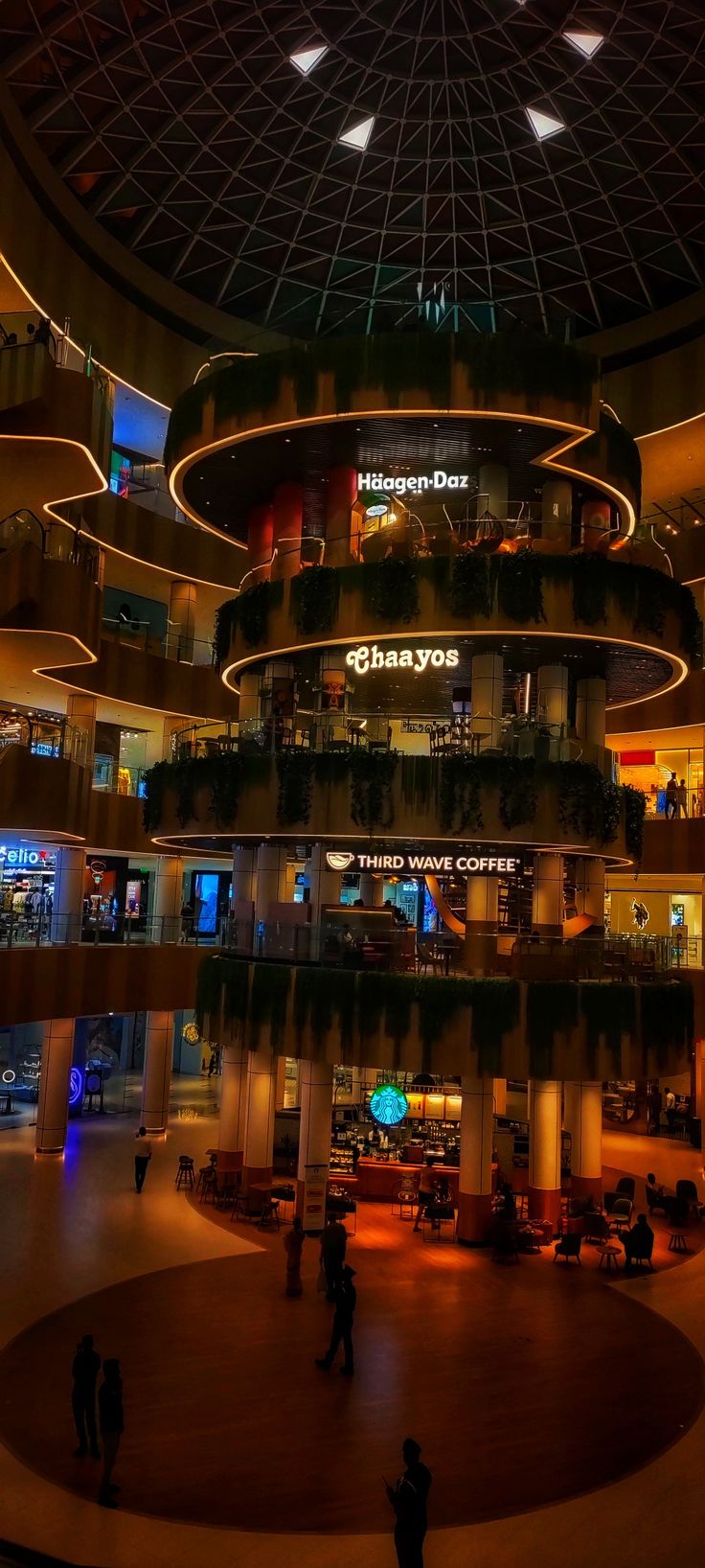 people are walking around in the lobby of a shopping mall at night with lights on