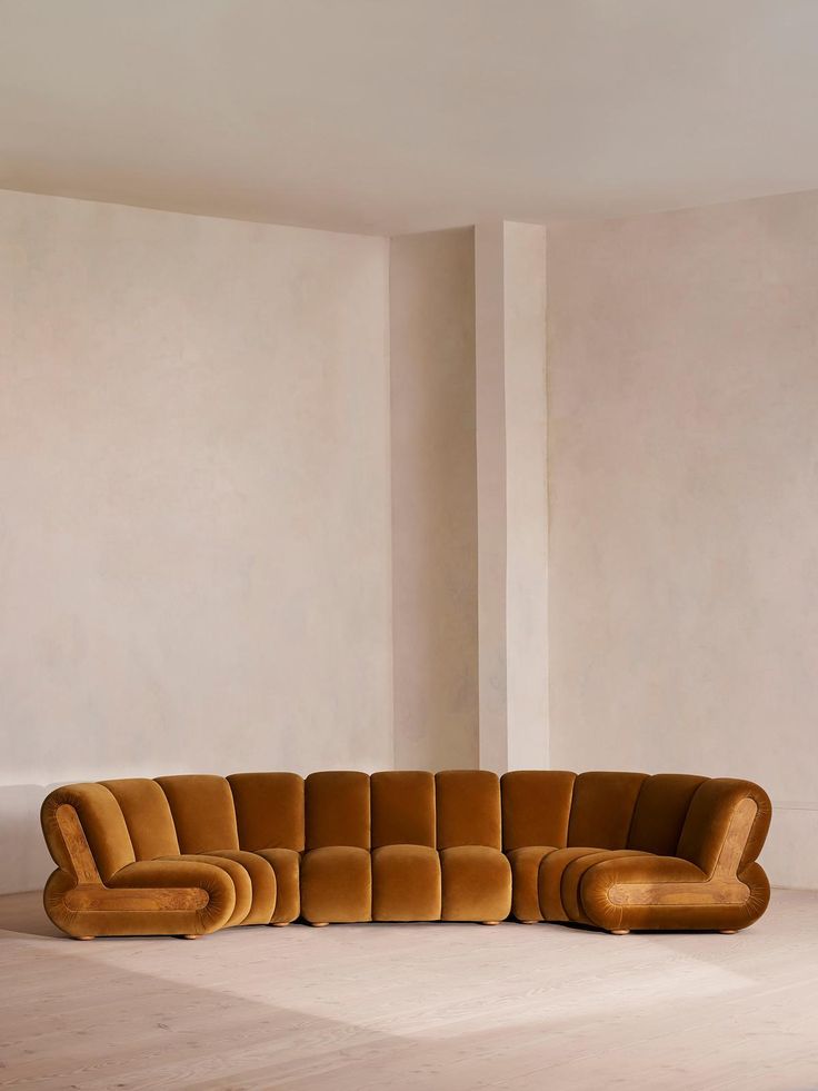 a large brown couch sitting on top of a white floor next to a tall wall