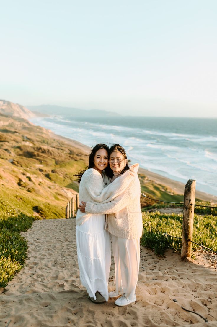 two women hugging each other on the beach