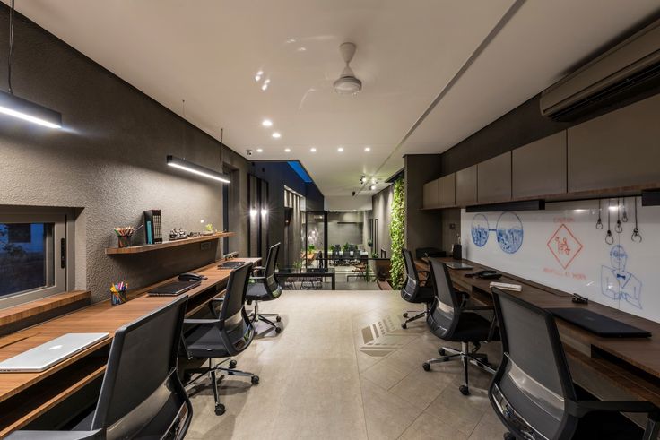 an office with desks and chairs in the middle, along with plants on the wall