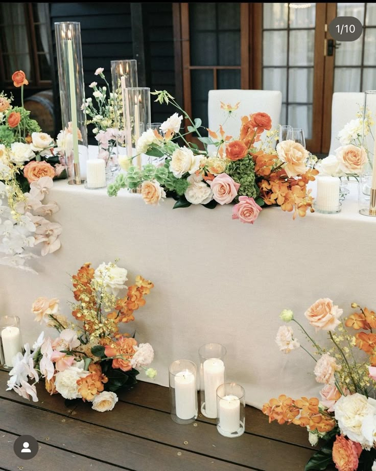 an arrangement of flowers and candles on a table