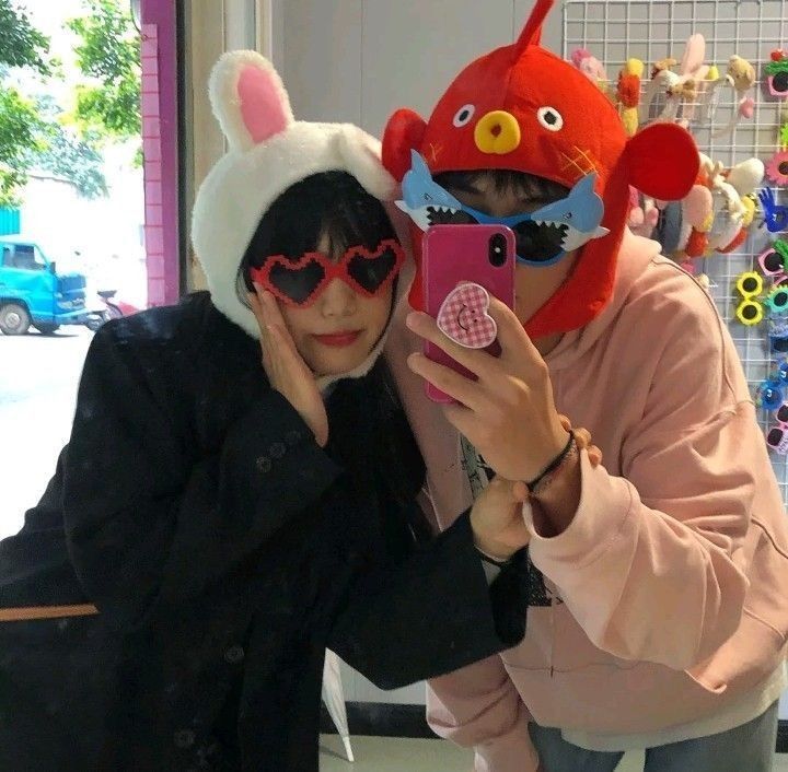 two people wearing animal masks taking a selfie with a cell phone in front of them