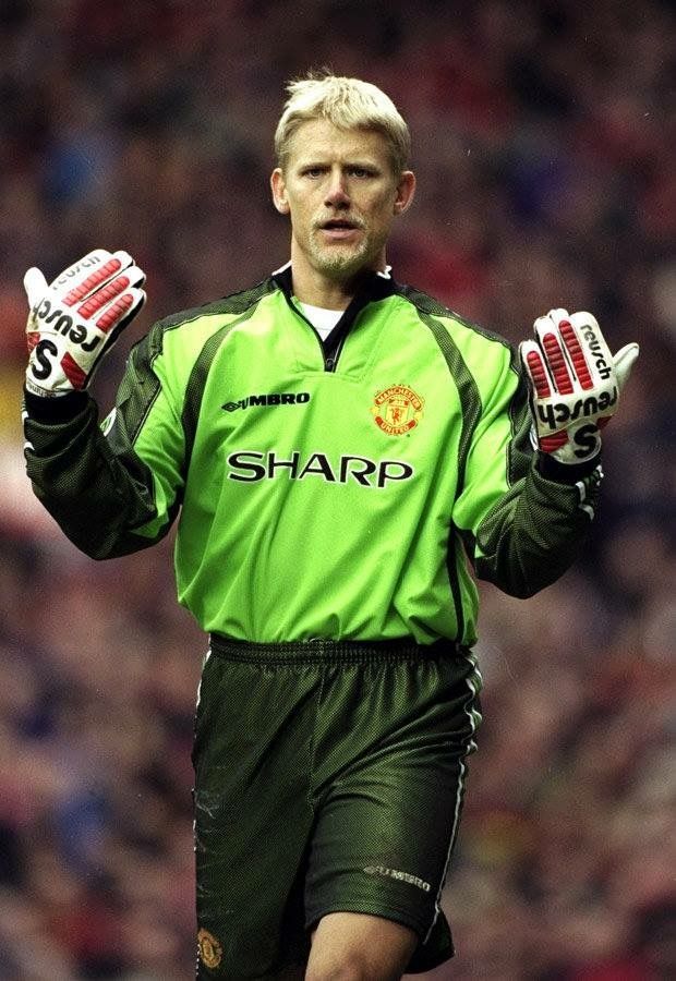 a soccer player with his hands in the air while wearing goalkeepers gear and gloves