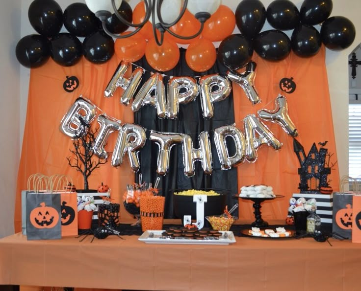 an orange and black birthday party with balloons, pumpkins, cake and decorations on the table