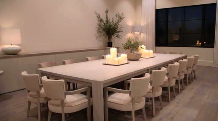 a long table with candles on it in the middle of a room filled with chairs