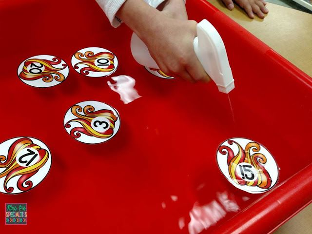 a child is playing with some stickers on a red tray at a table in front of them