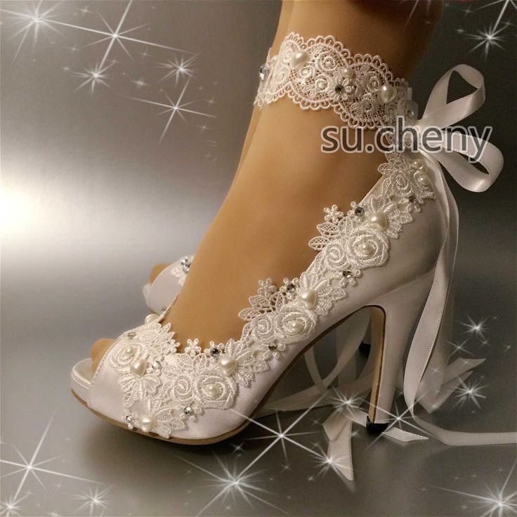 white bridal shoes with lace and bows on the heels are shown in front of a shiny