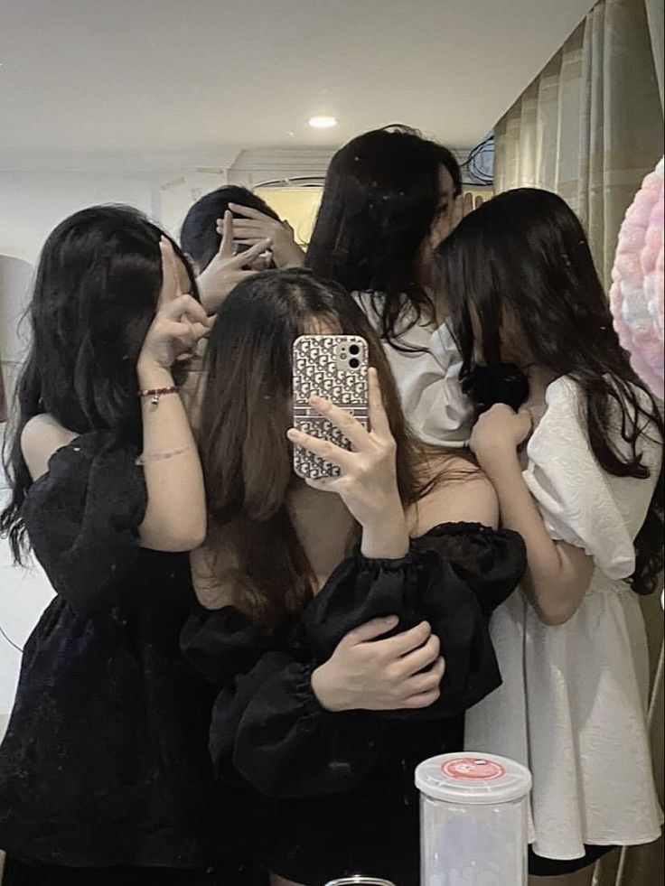 a group of young women standing next to each other in front of a mirror holding cell phones