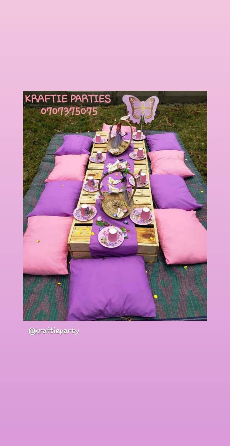 a table set up for a party with purple and pink plates, napkins and butterfly decorations