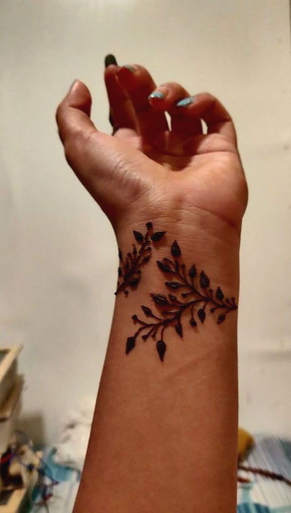 a woman's arm with a tattoo on it that has flowers and leaves all over it