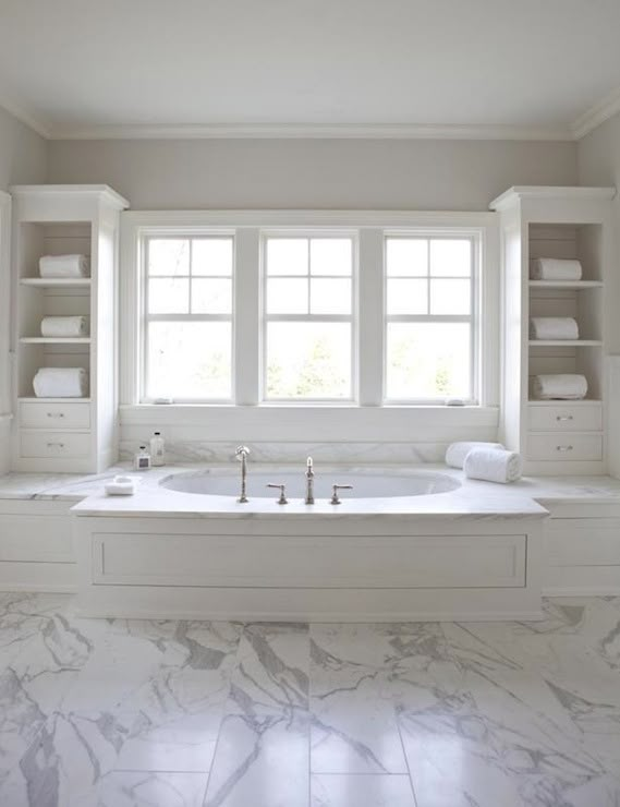 a large bathroom with marble floors and white walls, along with built - in shelving