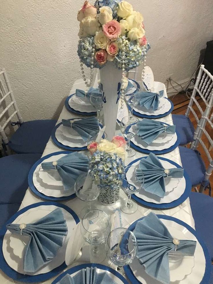 the table is set with blue and white plates, napkins, and flower centerpieces