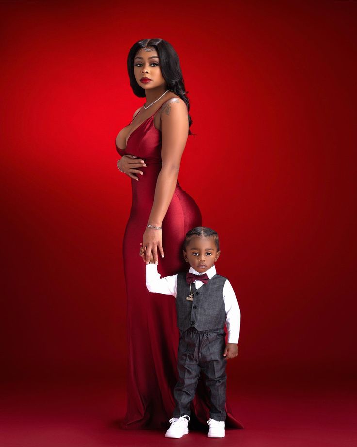 a woman in a red dress standing next to a little boy