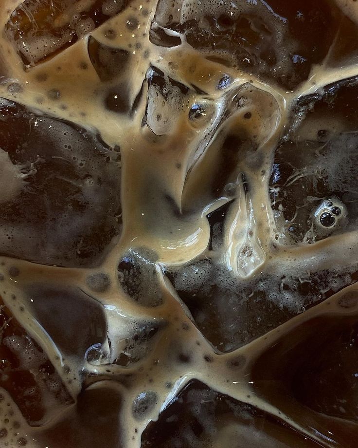 ice cubes with brown and white liquid on them in a bowl, top view