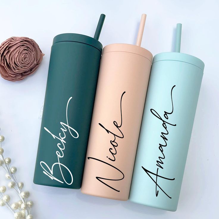 three personalized tumblers sitting next to each other on a white surface with flowers