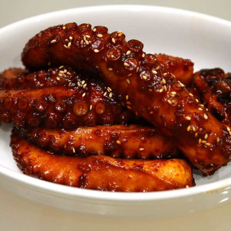 a white bowl filled with chicken wings covered in sesame seeds