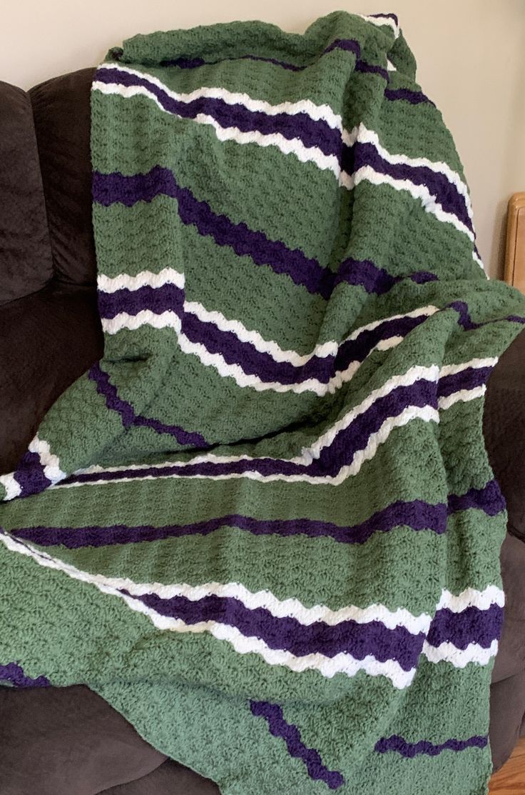 a green and purple blanket sitting on top of a couch