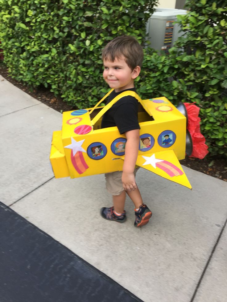 a little boy that is standing in the street with a toy plane on his back